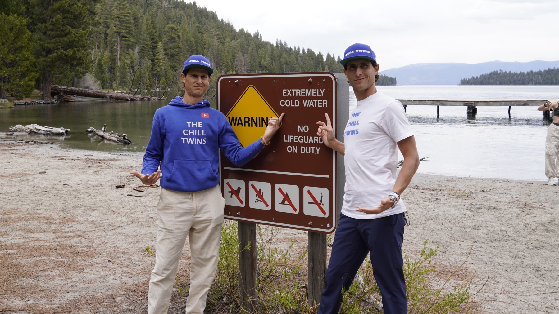 The Chill Twins beside an Extremely Cold Water warning sign at the lake